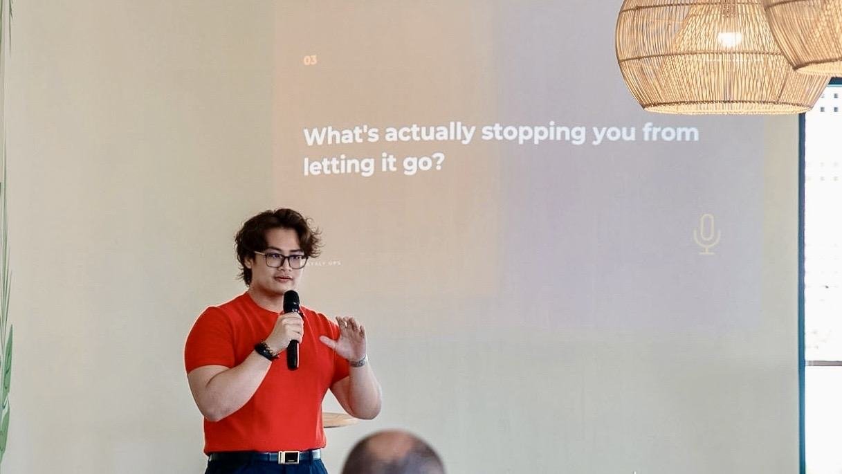 Adha Gozali speaking at a Dayaly Ops founder session, a slide behind him asking what is stopping founders from letting go.